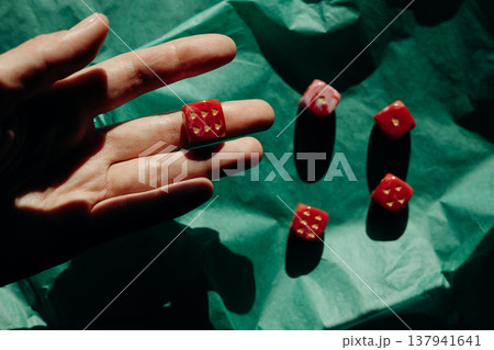 Hand holding red marble dice with gold heart pips over green paper. Romantic gambling concept, luck in love, Valentine's Day. Hand holding red marble dice with gold heart pips over green paper. Romantic gambling concept, luck in love, Valentine's Day. 137941641