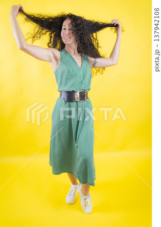 Woman smiling holding voluminous curly hair 137942108