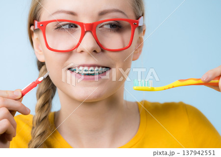 Woman smiling cleaning teeth with braces 137942551