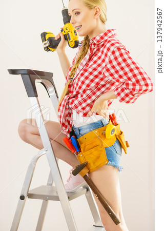Woman on ladder using drill Woman on ladder using drill 137942567