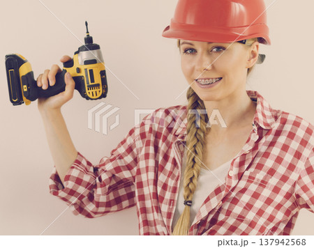 Woman wearing helmet using drill Woman wearing helmet using drill 137942568