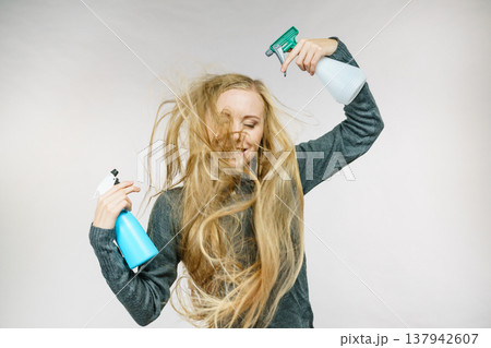 Female messy long hair holds spray bottle Female messy long hair holds spray bottle 137942607