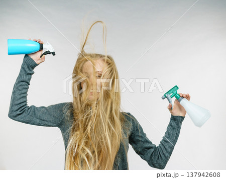 Female messy long hair holds spray bottle 137942608