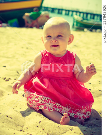 Little baby sitting and playing on beach 137942926