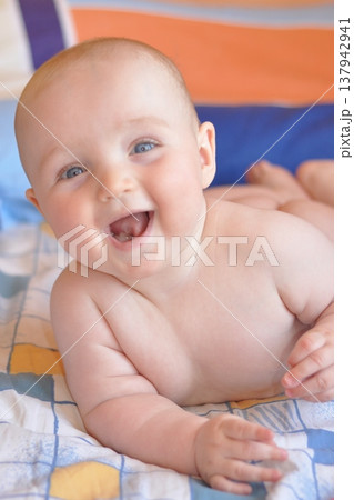 Baby Smiling Joyfully on a Colorful Bedspread 137942941