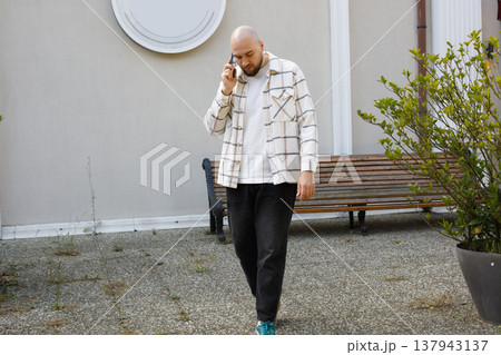 Businessman walking and talking on phone outdoors Businessman walking and talking on phone outdoors 137943137