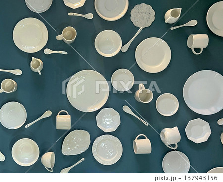 Collection of white dishes and utensils displayed on a dark wall in a modern setting Collection of white dishes and utensils displayed on a dark wall in a modern setting 137943156