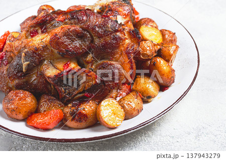 Pork knuckle baked with vegetables, new potatoes , on a white plate, homemade, no people, Pork knuckle baked with vegetables, new potatoes , on a white plate, homemade, no people, 137943279