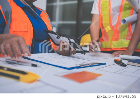 engineer and an architect reviewing blueprints and construction plans together at a bustling construction site engineer and an architect reviewing blueprints and construction plans together at a bustling construction site 137943359