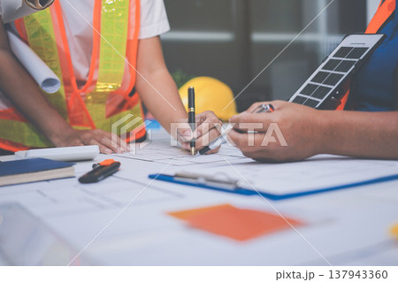 engineer and an architect reviewing blueprints and construction plans together at a bustling construction site engineer and an architect reviewing blueprints and construction plans together at a bustling construction site 137943360