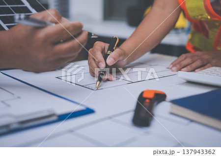 engineer and an architect reviewing blueprints and construction plans together at a bustling construction site 137943362