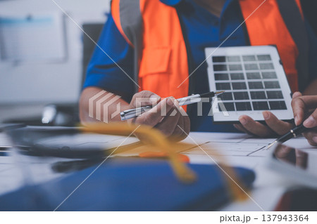 engineer and an architect reviewing blueprints and construction plans together at a bustling construction site 137943364
