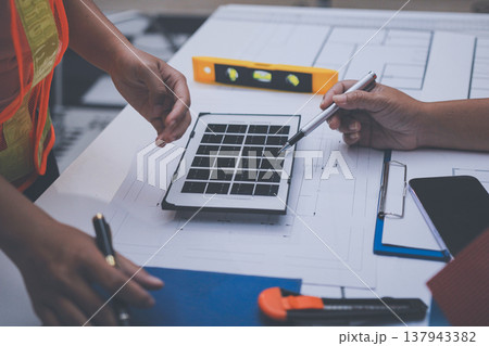 engineer and an architect reviewing blueprints and construction plans together at a bustling construction site 137943382