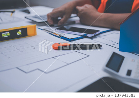 engineer and an architect reviewing blueprints and construction plans together at a bustling construction site 137943383