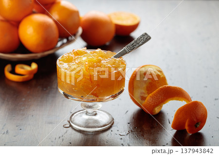 Orange jam in a glass dessert bowl on an old wooden table. 137943842