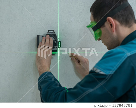 A man measures distance with a laser level. A man measures distance with a laser level. 137945791