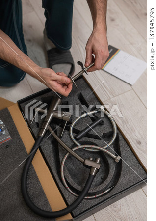 A plumber is replacing a faucet in the kitchen. A plumber is replacing a faucet in the kitchen. 137945795