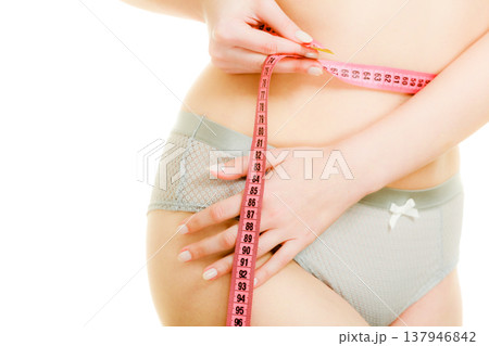 Woman in lingerie measuring her waist with measure tape. Woman in lingerie measuring her waist with measure tape. 137946842
