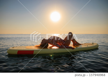 Young woman walking on sup board by the sea during summer vacation 137948968