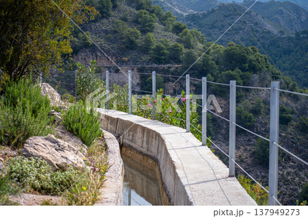 Scenic view of surrounding mountains and picturesque village from a hiking trail along an old irrigation ditch in Frigiliana, Spain. 137949273