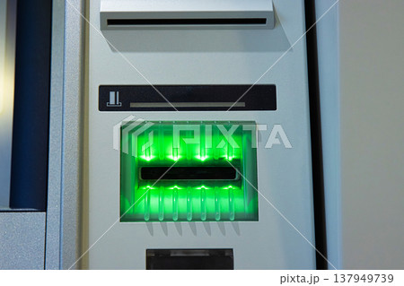 A closeup of a glowing green card slot of an ATM, ready to accept a transaction card. A closeup of a glowing green card slot of an ATM, ready to accept a transaction card. 137949739