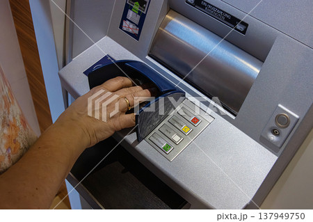 Person using the keypad of an ATM interface labeled in German to enter information or PIN for a secure transaction. Closeup of a hand over keypad pressing buttons Person using the keypad of an ATM interface labeled in German to enter information or PIN for a secure transaction. Closeup of a hand over keypad pressing buttons 137949750