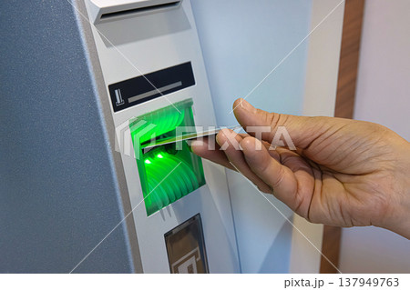 Closeup of a person hand inserting a bank card into an ATM machine slot for money withdrawal Closeup of a person hand inserting a bank card into an ATM machine slot for money withdrawal 137949763