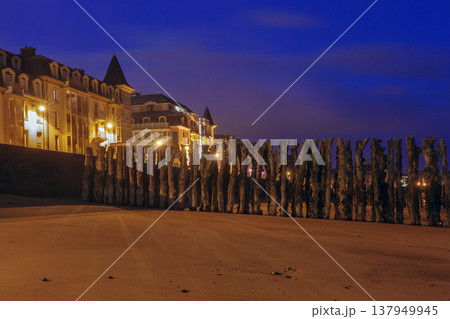 Wooden breakwaters and illuminated beachfront at night in Saint Malo France 137949945