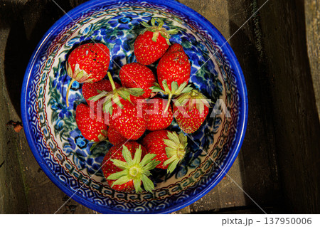 A colorful bowl of freshly picked strawberries in a wooden box, representing a homegrown harvest. 137950006