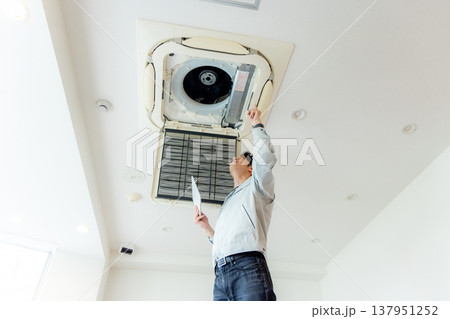 エアコンのメンテナンスをする作業員の男性 137951252