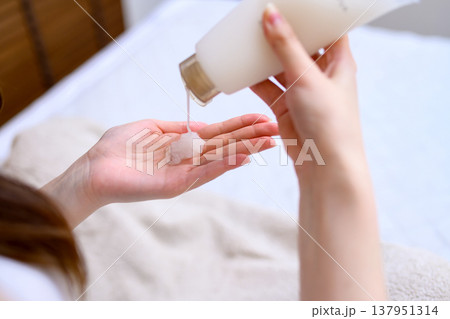 手のひらにハンドクリームを出す若い女性　ハンドジェル　 137951314