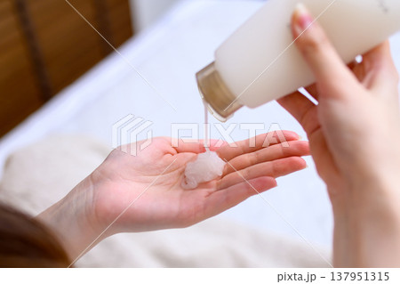 手のひらにハンドクリームを出す若い女性　ハンドジェル　トリミングアップ 137951315