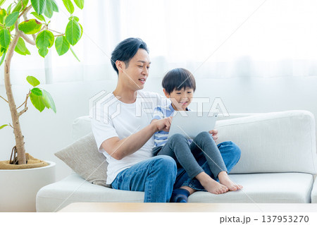 ソファーに座ってタブレットを見る家族 137953270