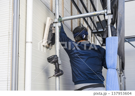 戸建て家屋の外壁修繕工事 新しいサイディングを貼り付ける職人 外張り断熱リフォーム 戸建て家屋の外壁修繕工事 新しいサイディングを貼り付ける職人 外張り断熱リフォーム 137953604