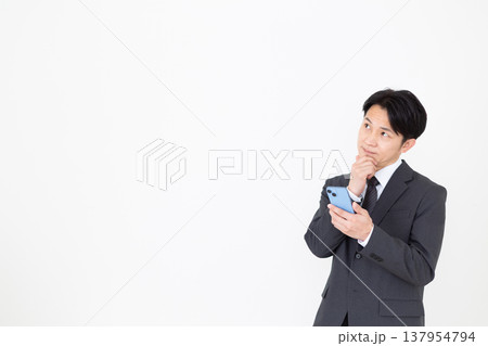 スマホを見ながら考えるミドル男性ビジネスマン スマホを見ながら考えるミドル男性ビジネスマン 137954794