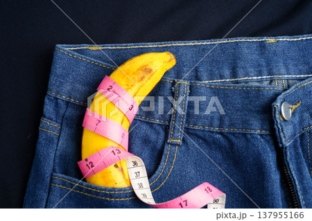 Banana with measuring tape on jean trousers, penis health. 137955166