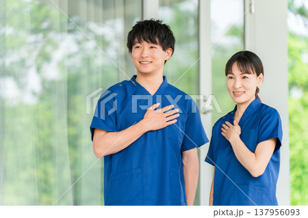 病院・施設の前にいるスクラブを着た医療従事者の男女スタッフ(信頼,自信) 病院・施設の前にいるスクラブを着た医療従事者の男女スタッフ(信頼,自信) 137956093