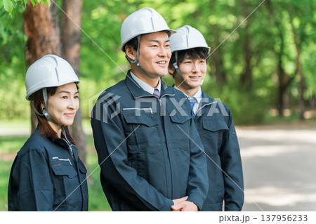 作業現場,建築現場,建設現場にいるヘルメットと作業着姿の男女スタッフ 137956233