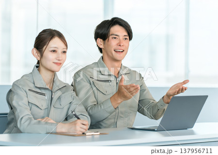 会議室で面談,面接,ミーティングをする作業着姿の男女スッタフ 137956711