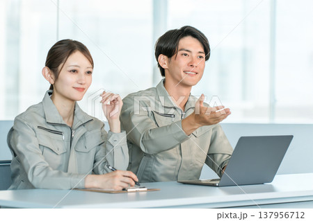 会議室で面談,面接,ミーティングをする作業着姿の男女スッタフ 137956712