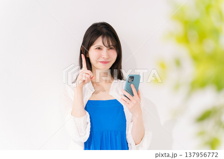 スマートフォンを持つ女性　指差し 137956772