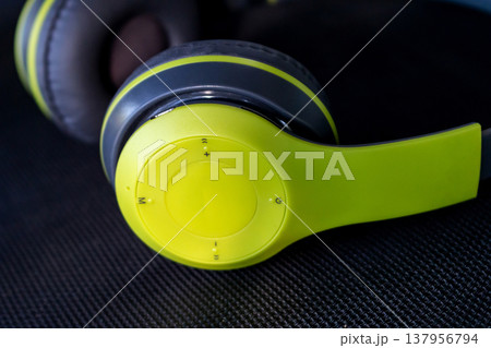 close up of lime green and black wireless headphones on dark background 137956794