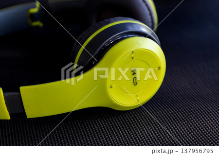 close up of lime green and black wireless headphones on dark background close up of lime green and black wireless headphones on dark background 137956795
