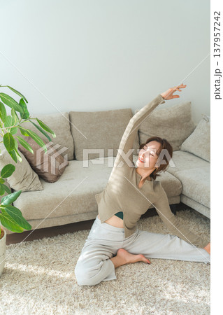 日差しの入るリビングでヨガ,ストレッチをするヨガウェア姿の女性 137957242
