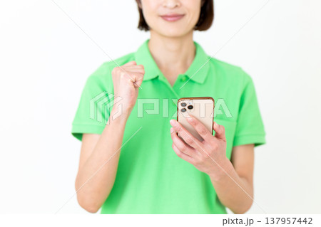 スマートフォンを見てガッツポーズするミドル女性の介護福祉士 スマートフォンを見てガッツポーズするミドル女性の介護福祉士 137957442