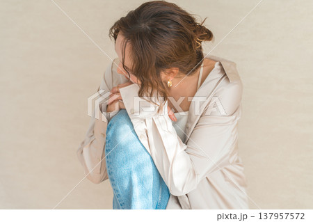 膝を抱えながら俯くおしゃれな女性(モデル,ファッションフォト,美容,ビューティ) 膝を抱えながら俯くおしゃれな女性(モデル,ファッションフォト,美容,ビューティ) 137957572