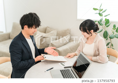 訪問販売で女性客に書類を使ってプランを説明するビジネスマン 訪問販売で女性客に書類を使ってプランを説明するビジネスマン 137958793
