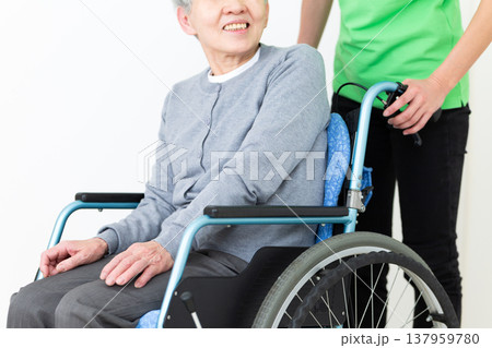車椅子に乗ったお年寄りを介助する介護福祉士 137959780
