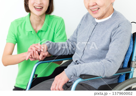 車椅子に乗ったお年寄りを介助する介護福祉士 137960002