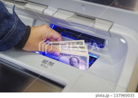 ATMからお金を引き出す男性の手元 ATMからお金を引き出す男性の手元 137960035
